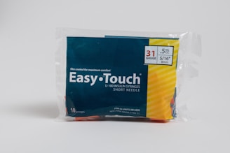 A package of Easy Touch U-100 insulin syringes is displayed. It contains 10 syringes with 31 gauge, 5/16 inch length, and 0.5 mL capacity. The packaging features a combination of dark blue and yellow colors, with text emphasizing comfort and specifications.