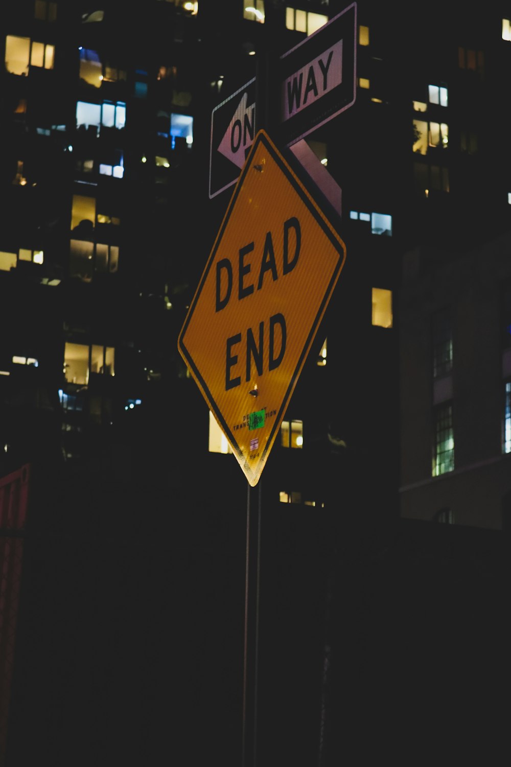 a yellow dead end sign sitting next to a tall building