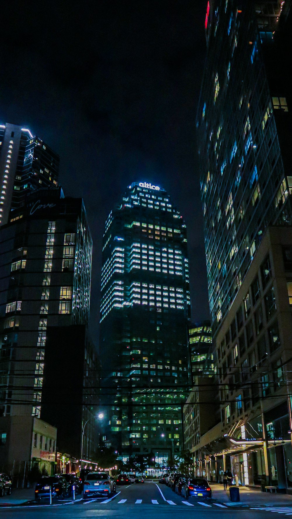 a city street at night with a lot of tall buildings