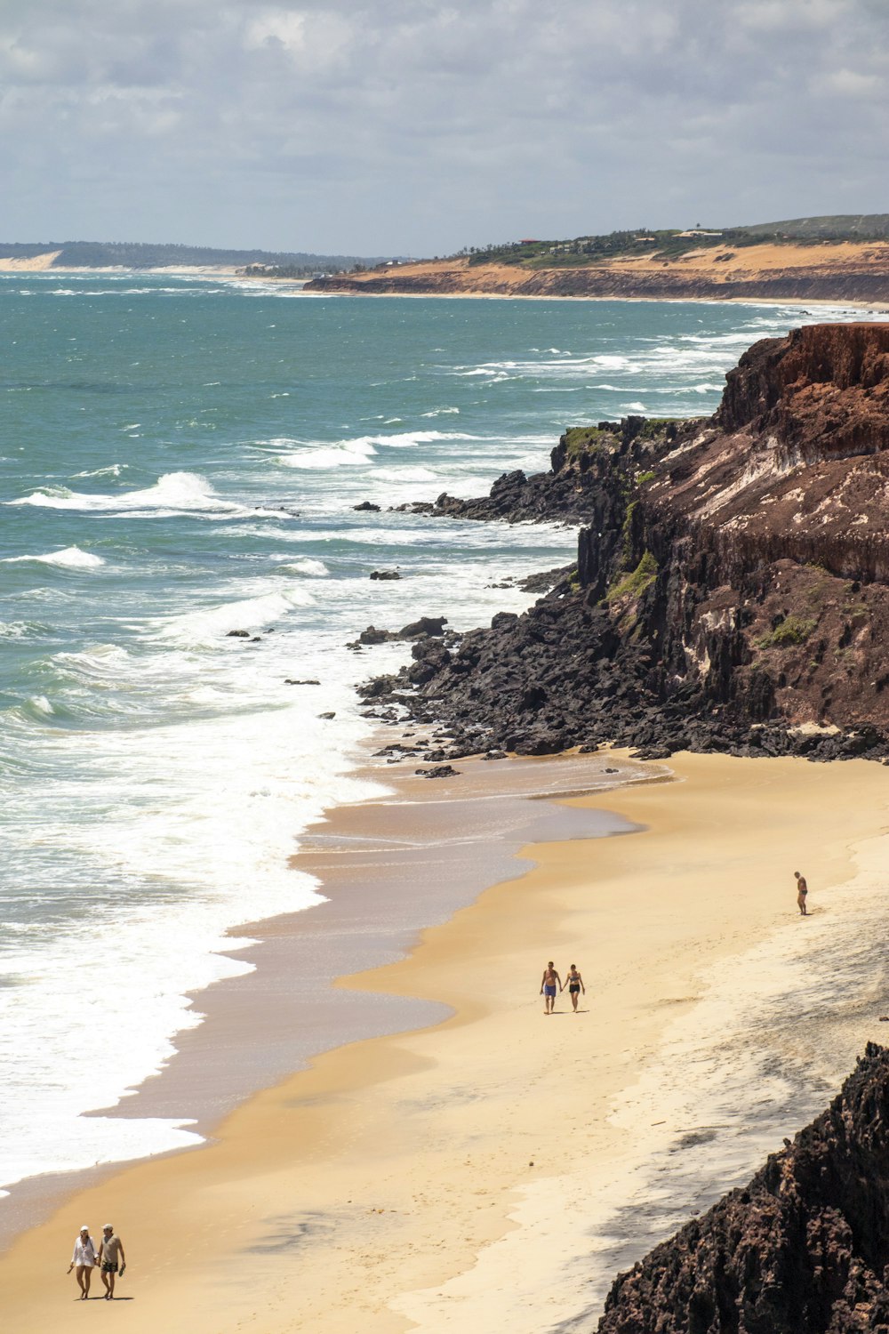 a group of people riding horses down a beach