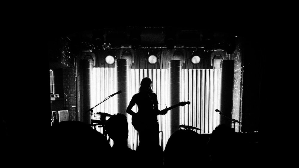a woman standing in front of a stage with a guitar