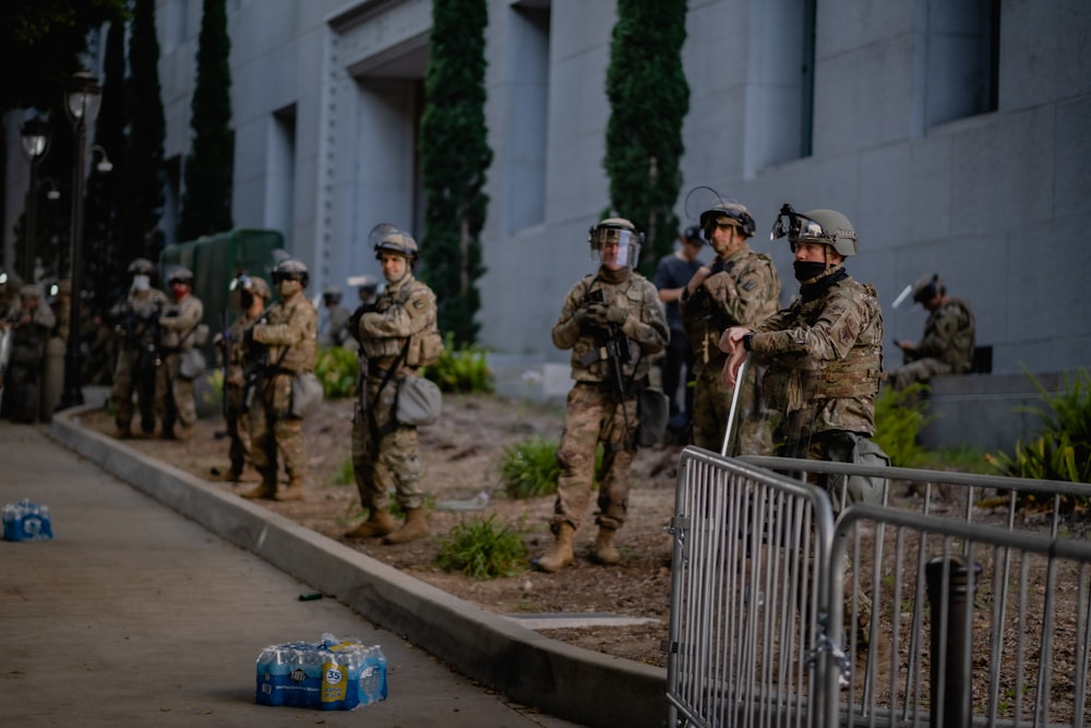 a group of people on a sidewalk near a fence