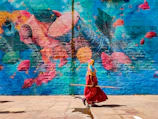 a woman in a red dress is holding a stick in front of a colorful wall
