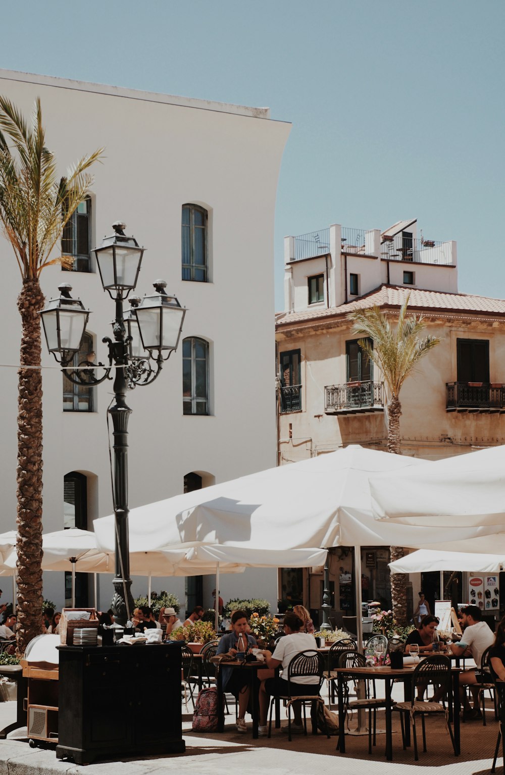 a group of people sitting at tables under umbrellas