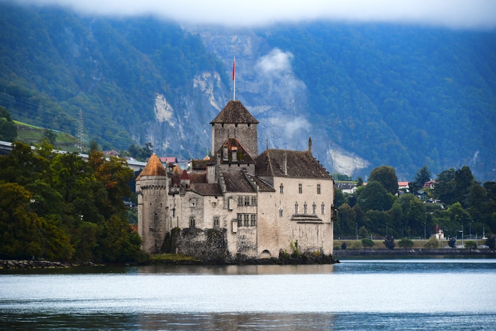 a castle sitting on top of a lake surrounded by mountains
