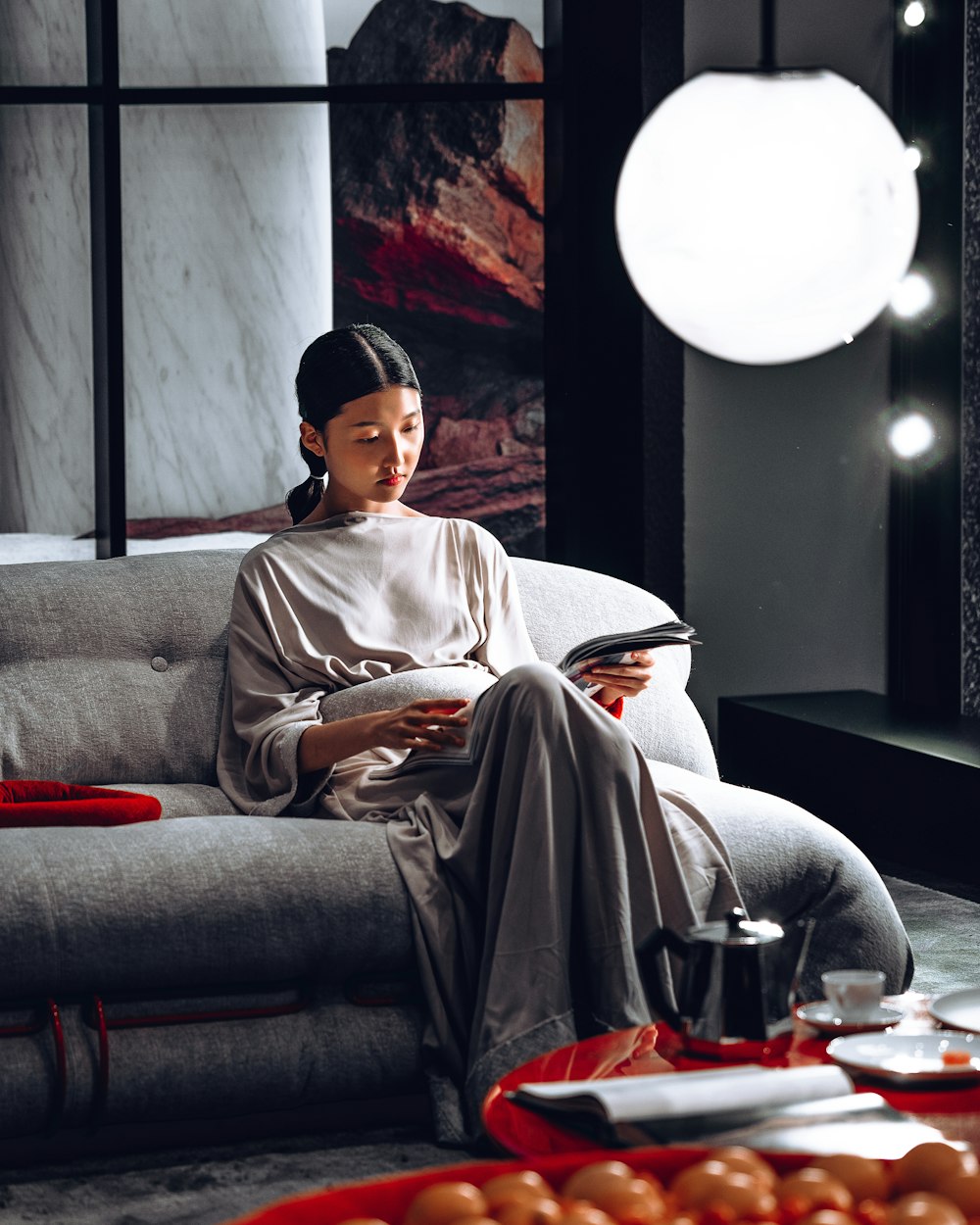 a woman sitting on a couch reading a book