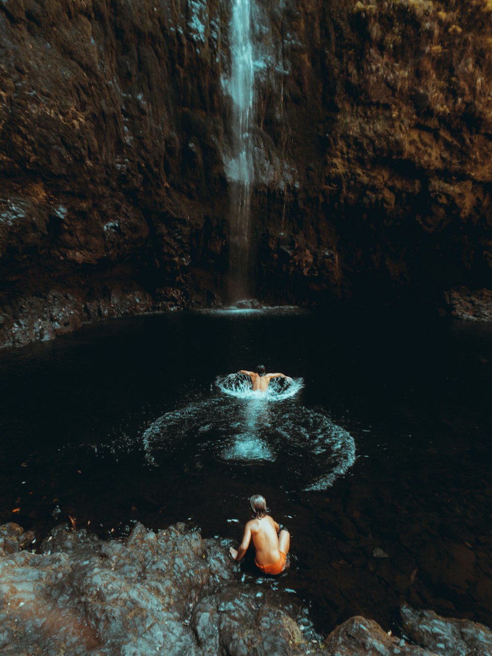 a person swimming in a pool in front of a waterfall