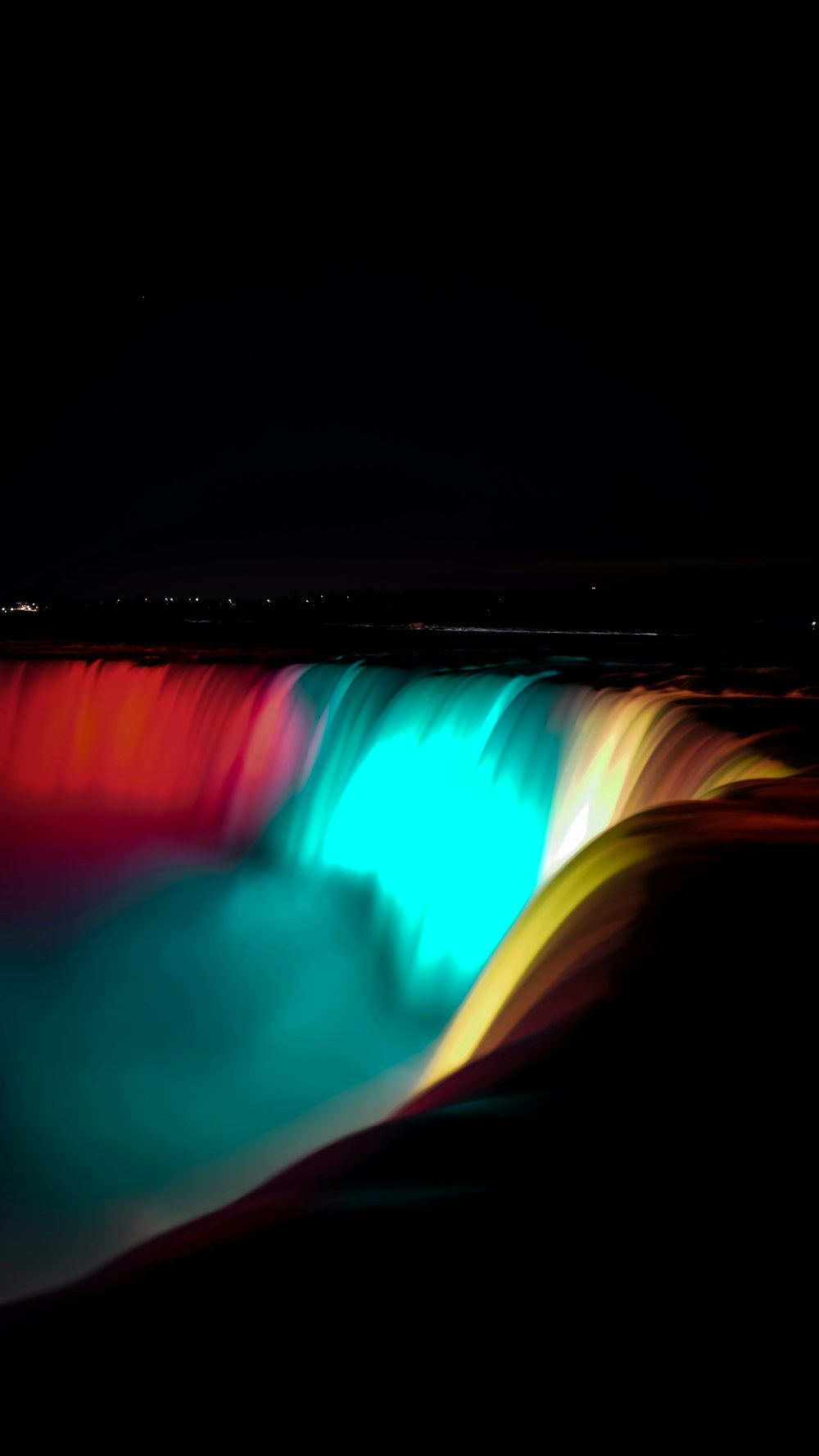 a colorful waterfall is lit up in the dark