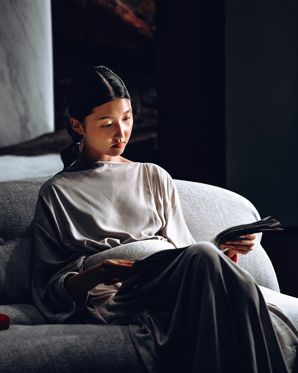 a woman sitting on a couch looking at a book