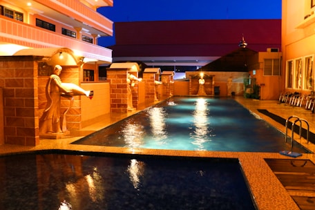 A commercial swimming pool with crystal-clear water and elegant lighting at dusk.
