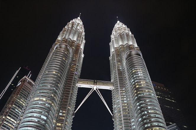 two very tall buildings towering over a city at night