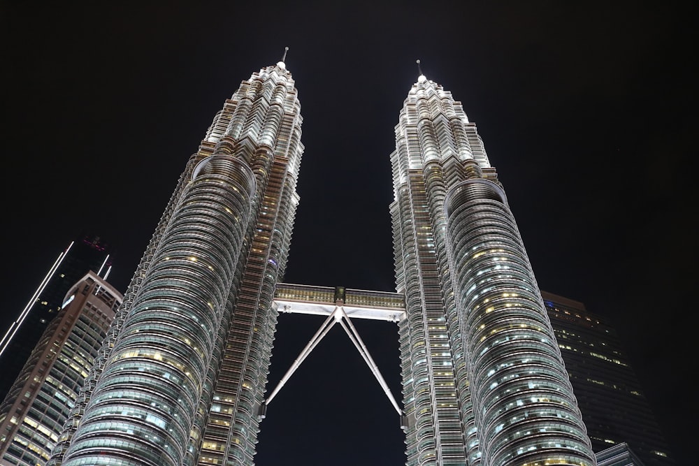 two very tall buildings towering over a city at night