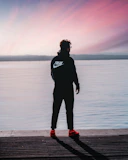 a man standing on a dock next to a body of water