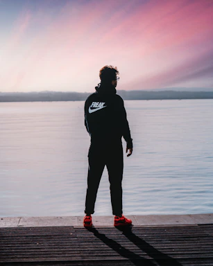 a man standing on a dock next to a body of water