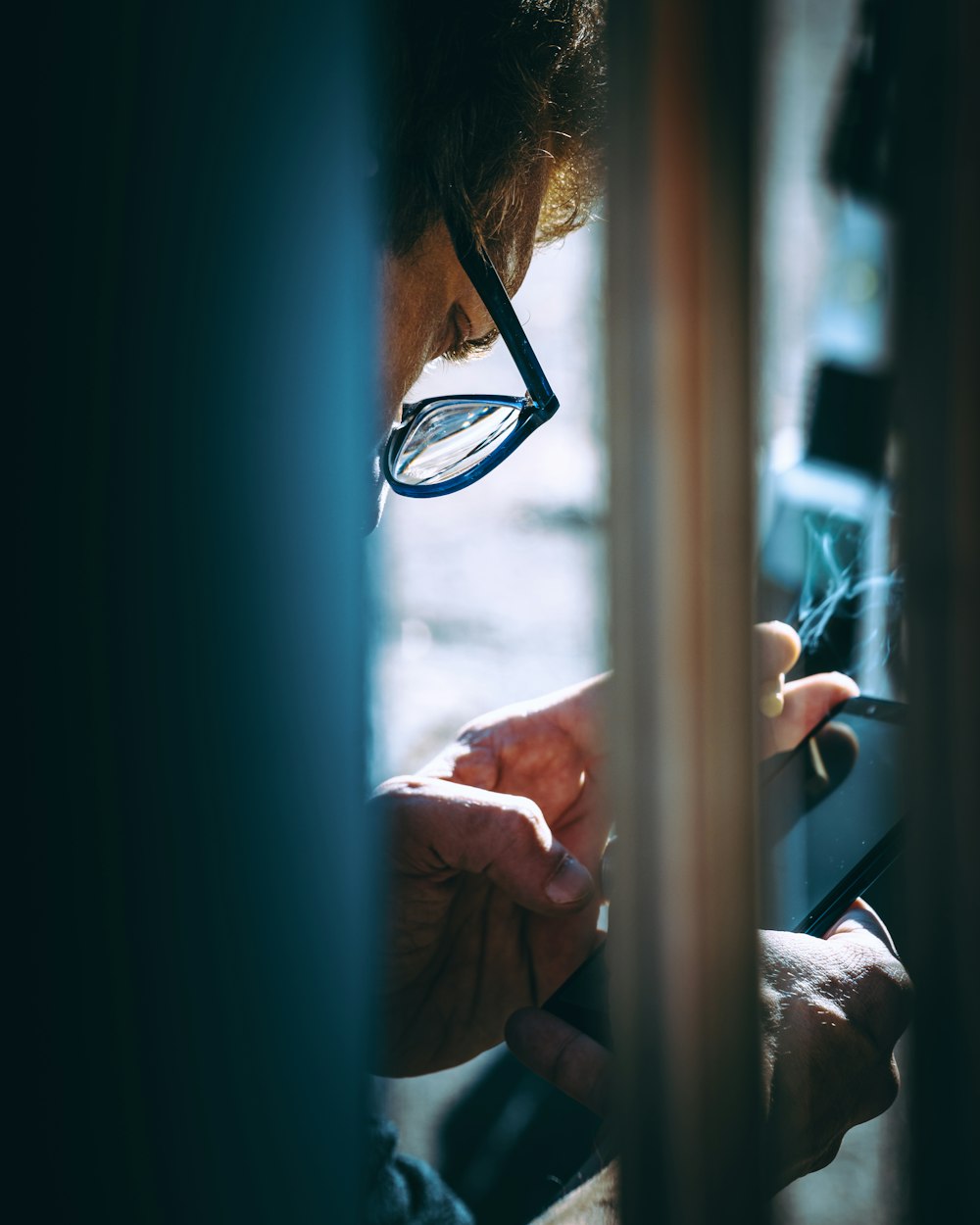 a man wearing glasses looking at a cell phone