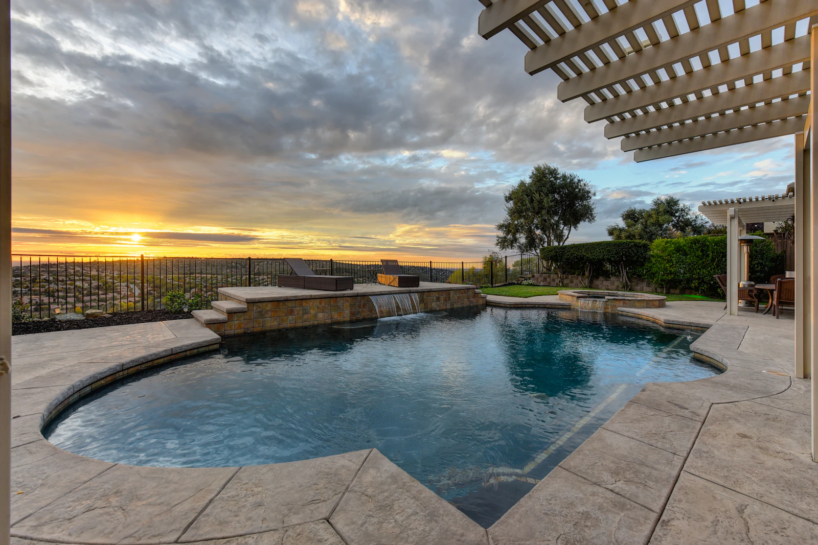 A raised stone spa spilling into a pool at golden hour