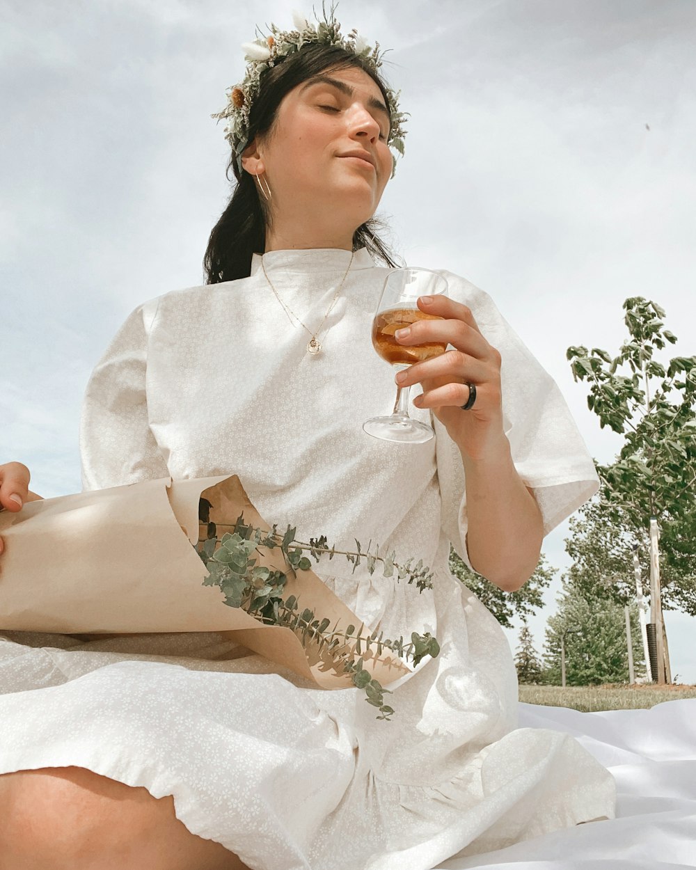 Una mujer con un vestido blanco sosteniendo una copa de vino