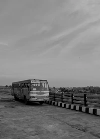 A comfortable tourist bus parked near a coastal area with palm trees.