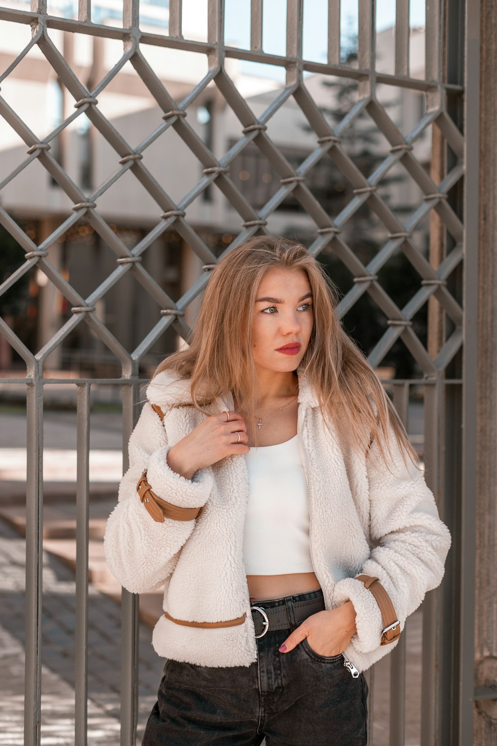 a woman standing in front of a metal fence