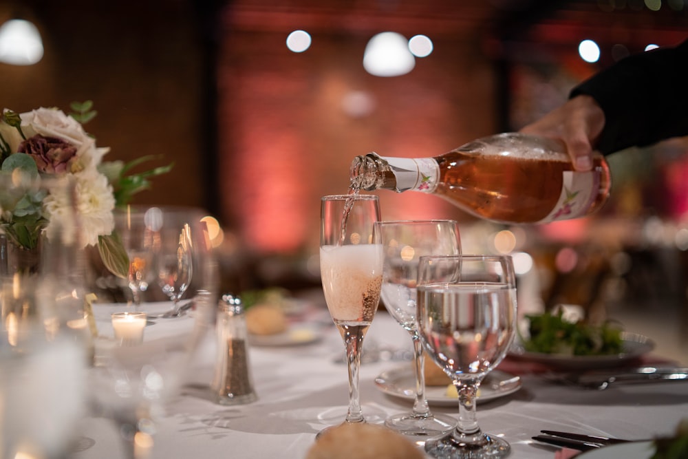 a person pouring wine into a glass on a table