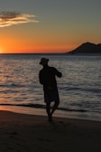 a man standing on top of a beach next to the ocean