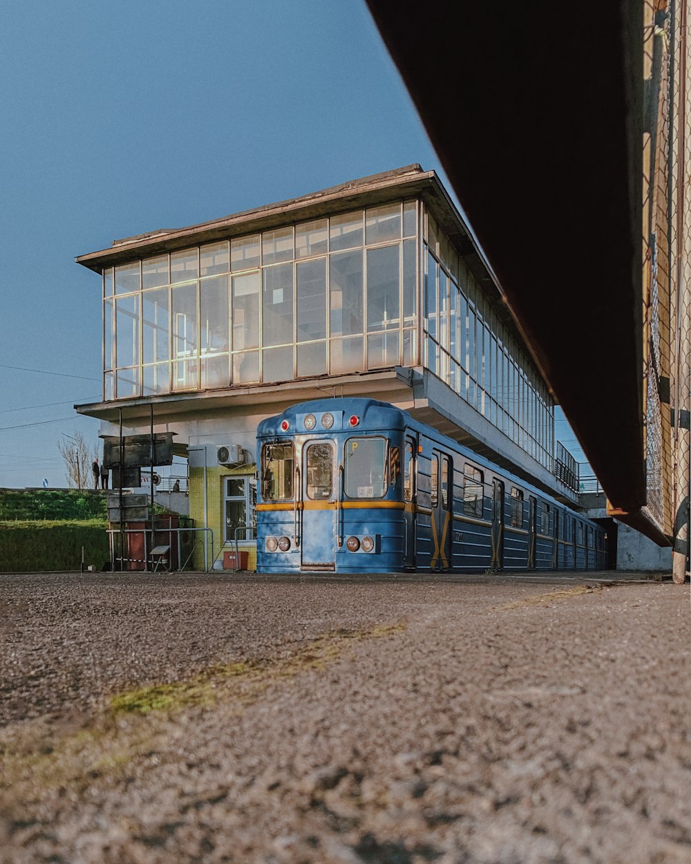 a blue train is parked in front of a building