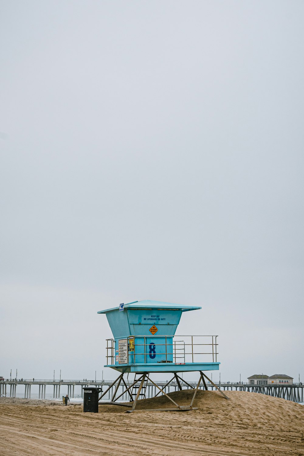 Un poste de sauveteur sur une plage avec une jetée en arrière-plan