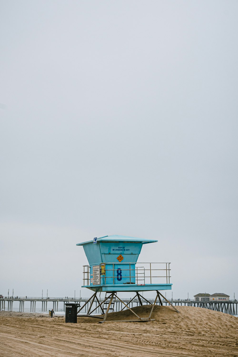 a lifeguard stand on a beach with a pier in the background