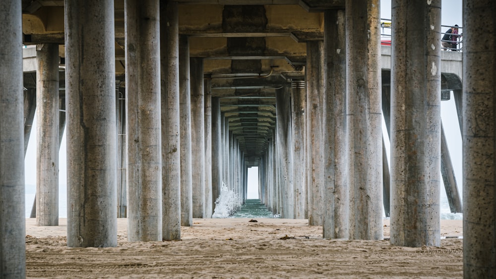 une longue rangée de piliers en bois au sommet d’une plage de sable
