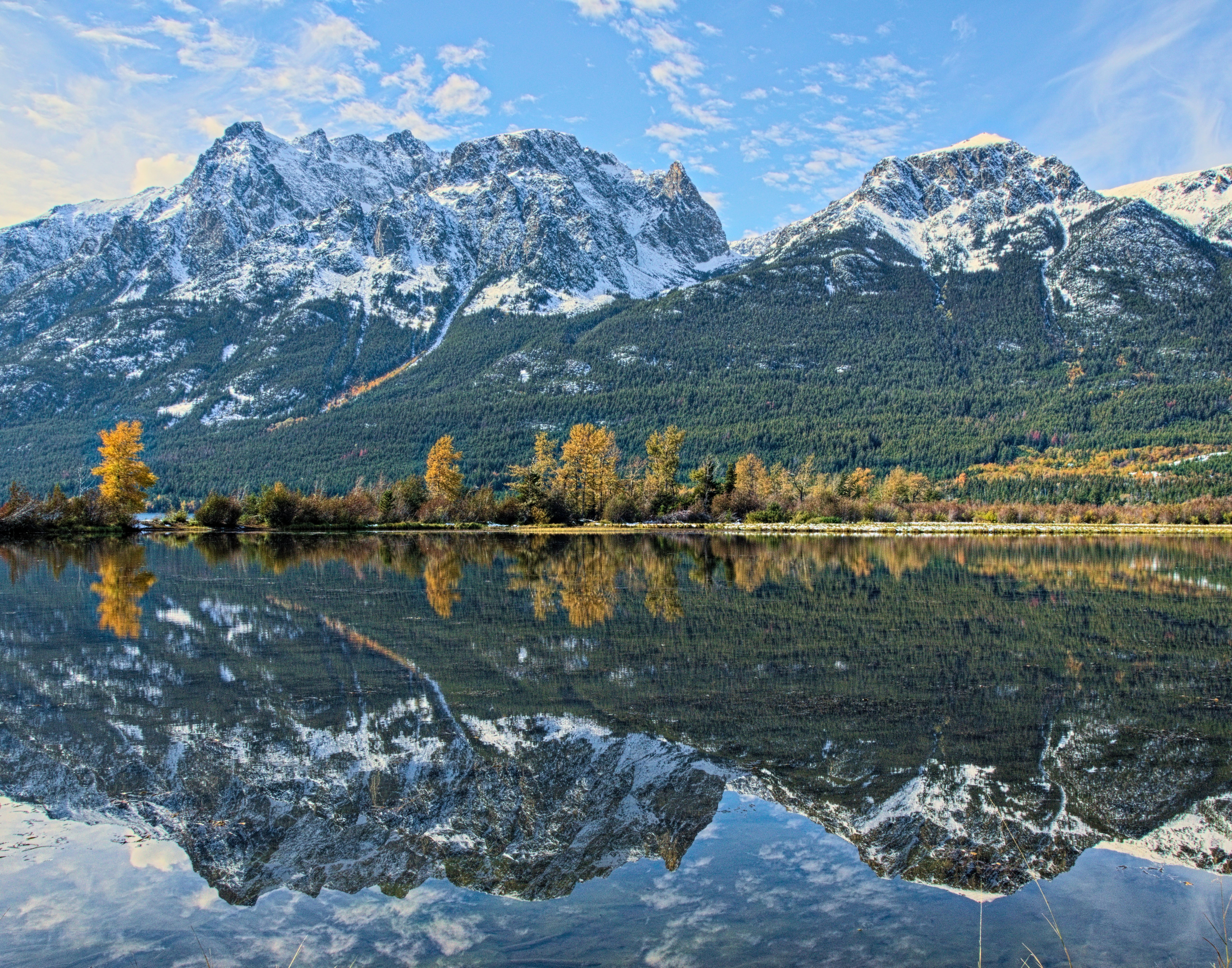 Une chaîne de montagnes se reflète dans l’eau calme d’un lac