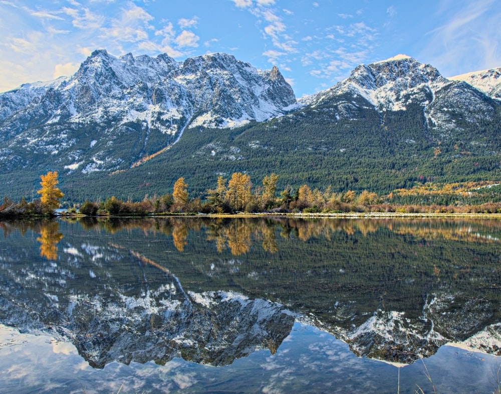 uma cordilheira é refletida na água parada de um lago