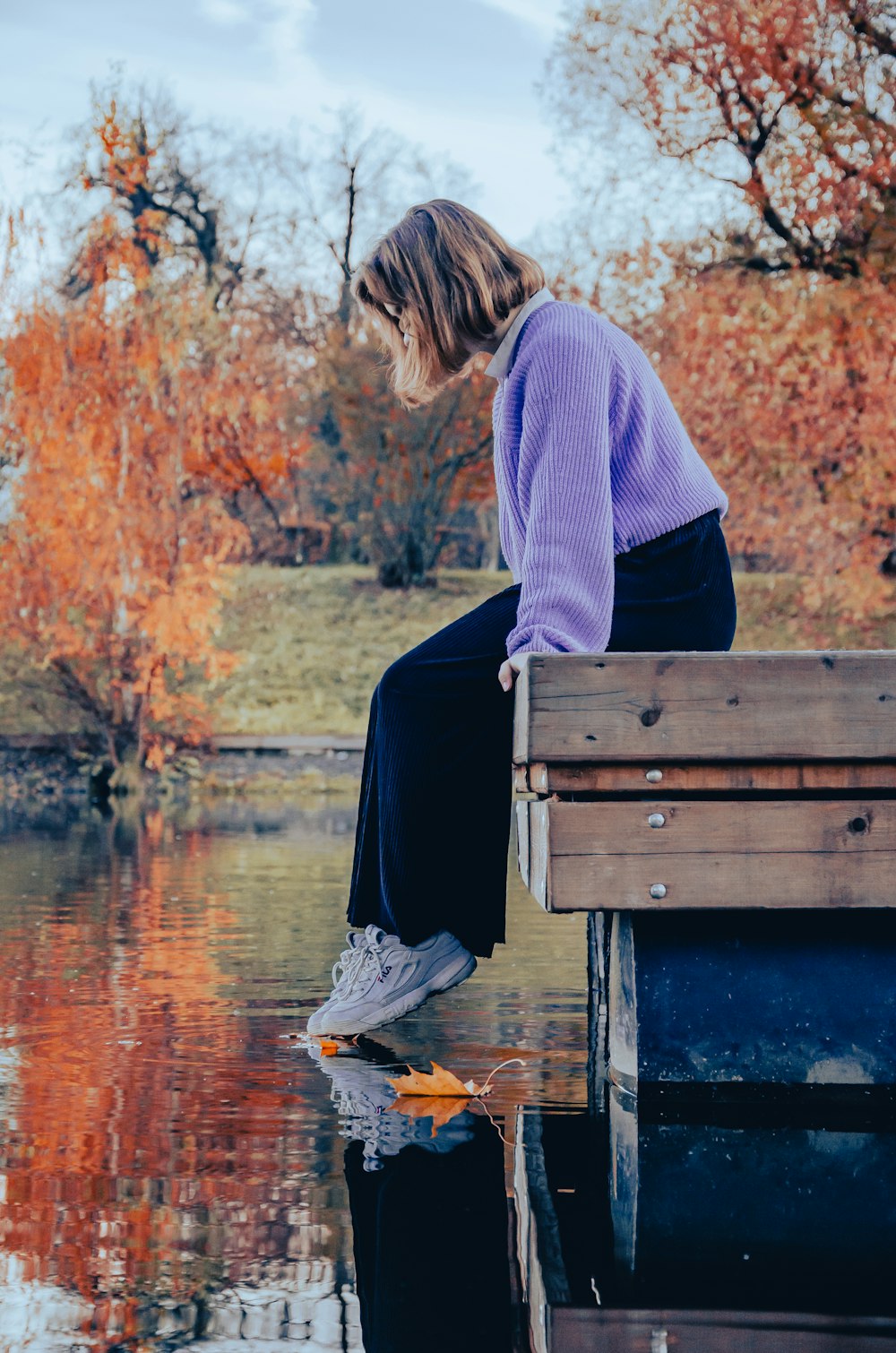 a woman sitting on a bench next to a body of water