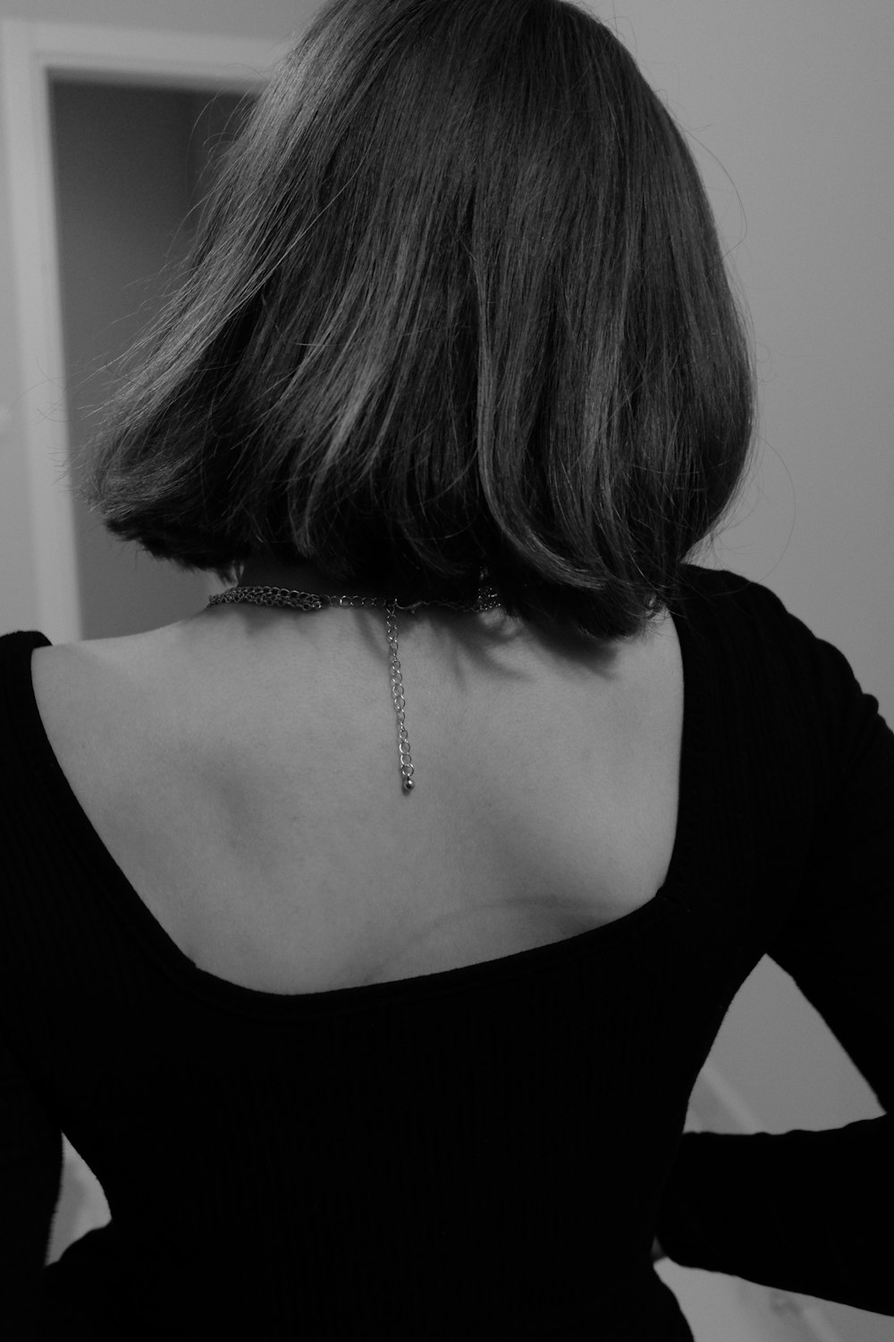 Una mujer con una camisa negra con una cadena en la espalda