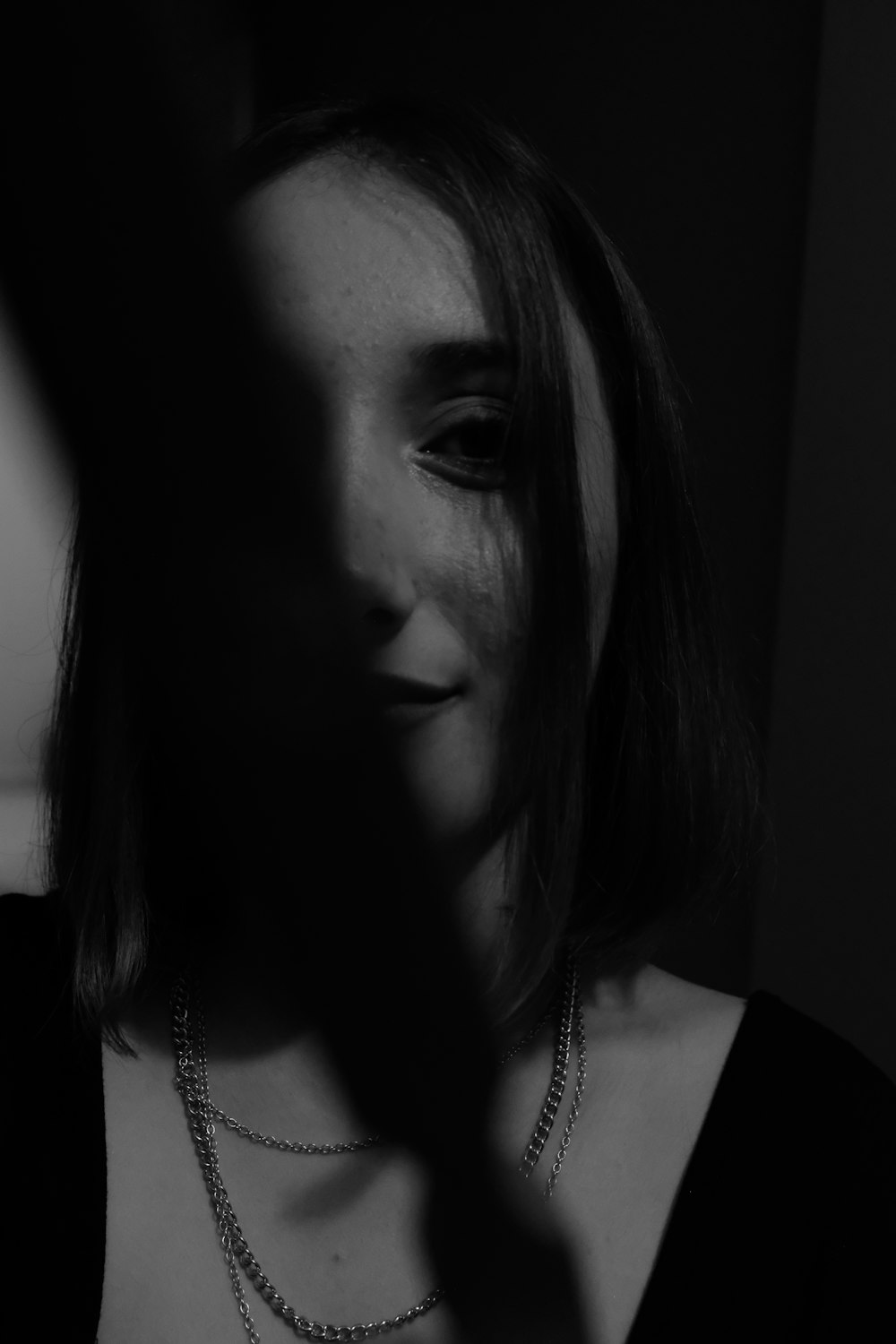 a woman in a dark room with a necklace on