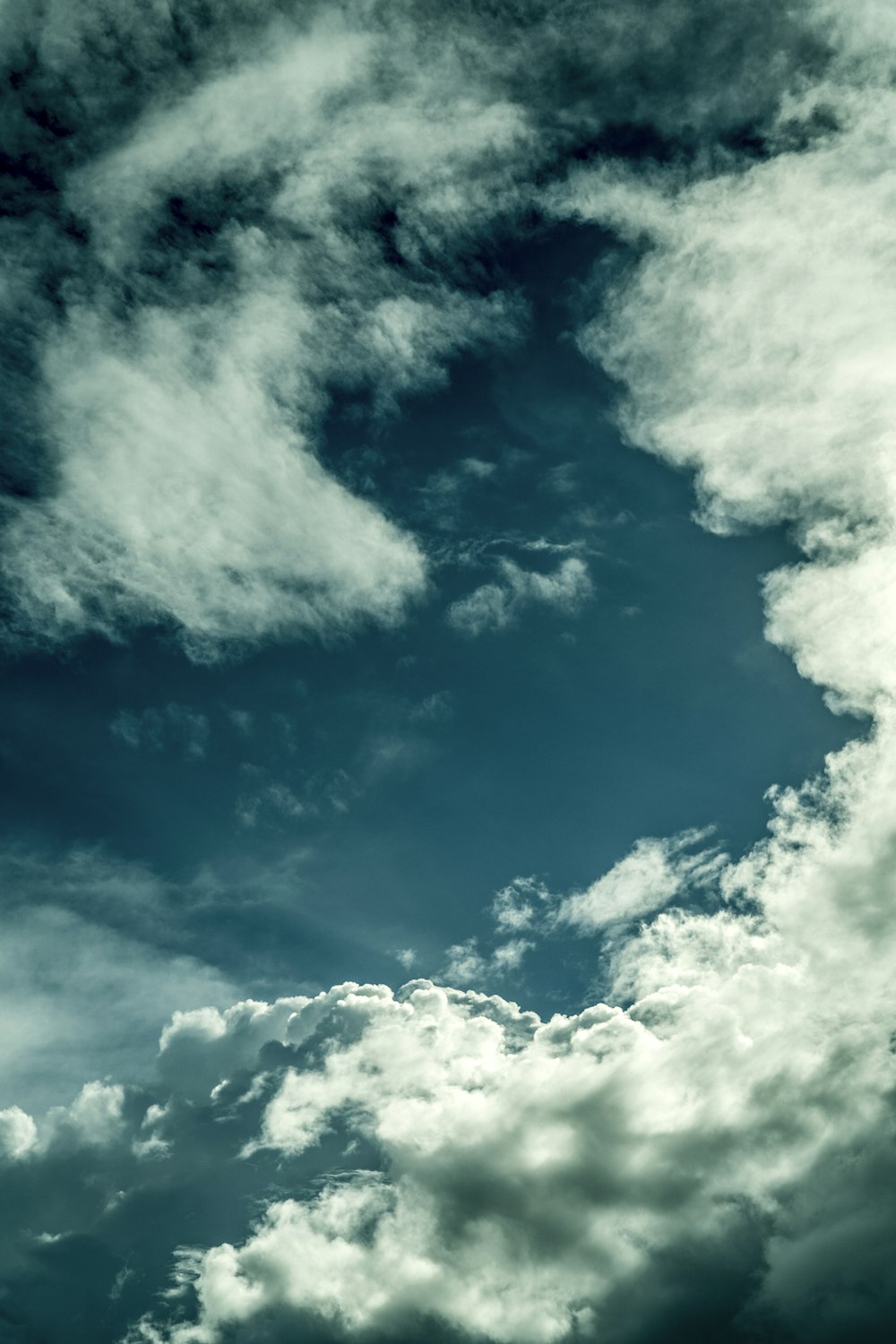 a plane flying through a cloudy blue sky