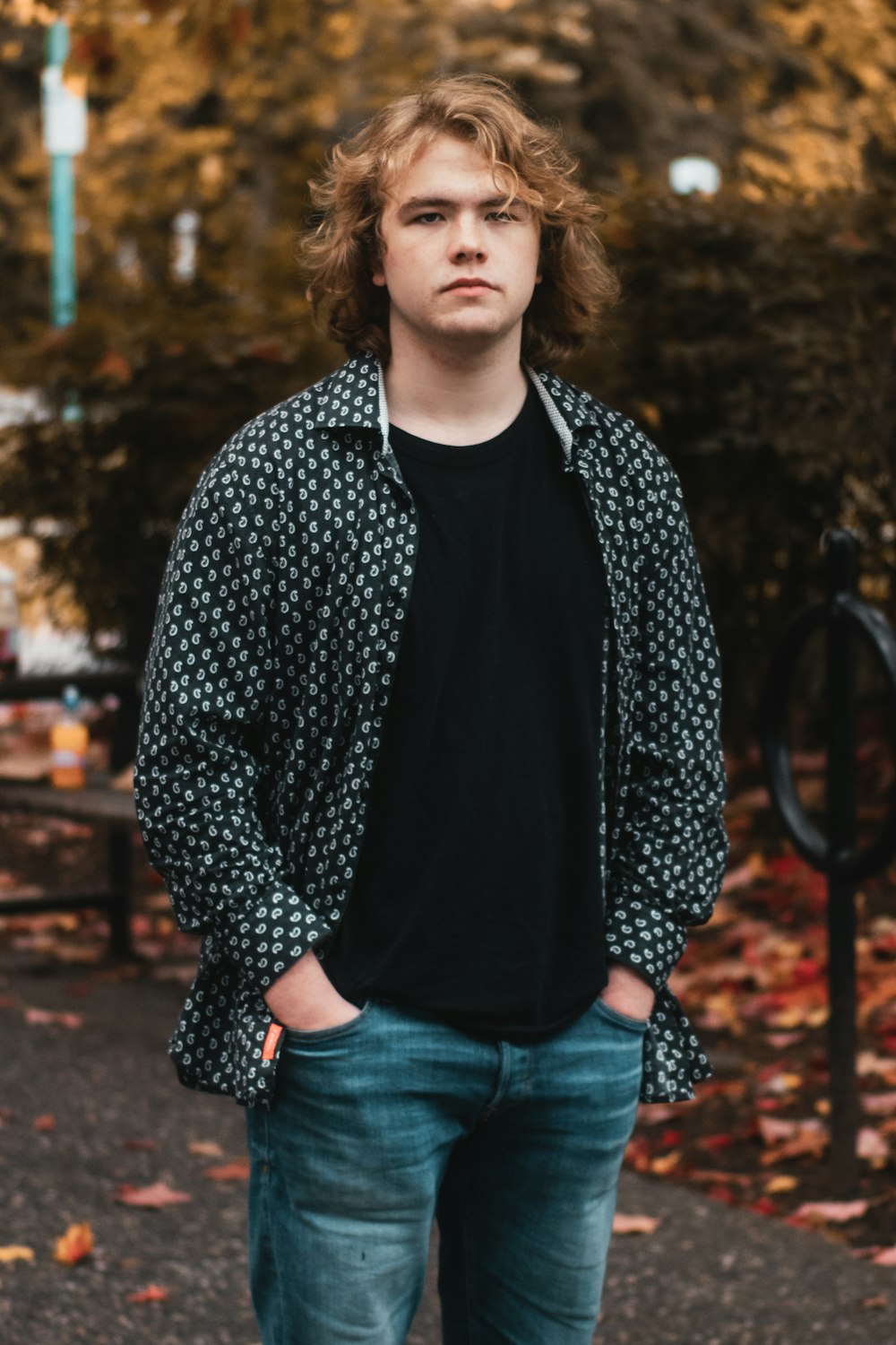 a young man standing in front of a tree