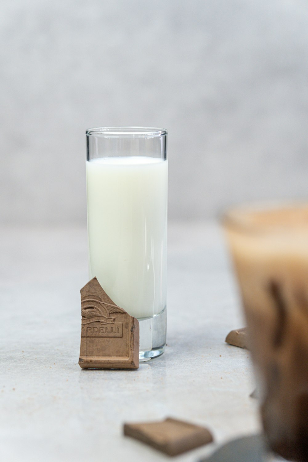 a glass of milk sitting next to a wooden block