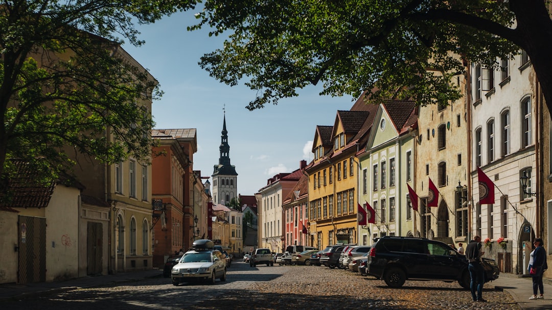 a city street lined with parked cars and tall buildings,