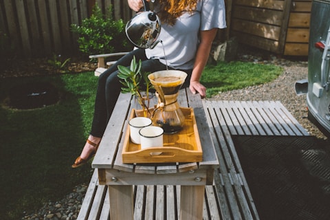 a woman sitting on a table with a coffee pot