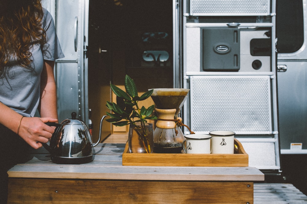 a woman standing next to a table with a tea pot on it