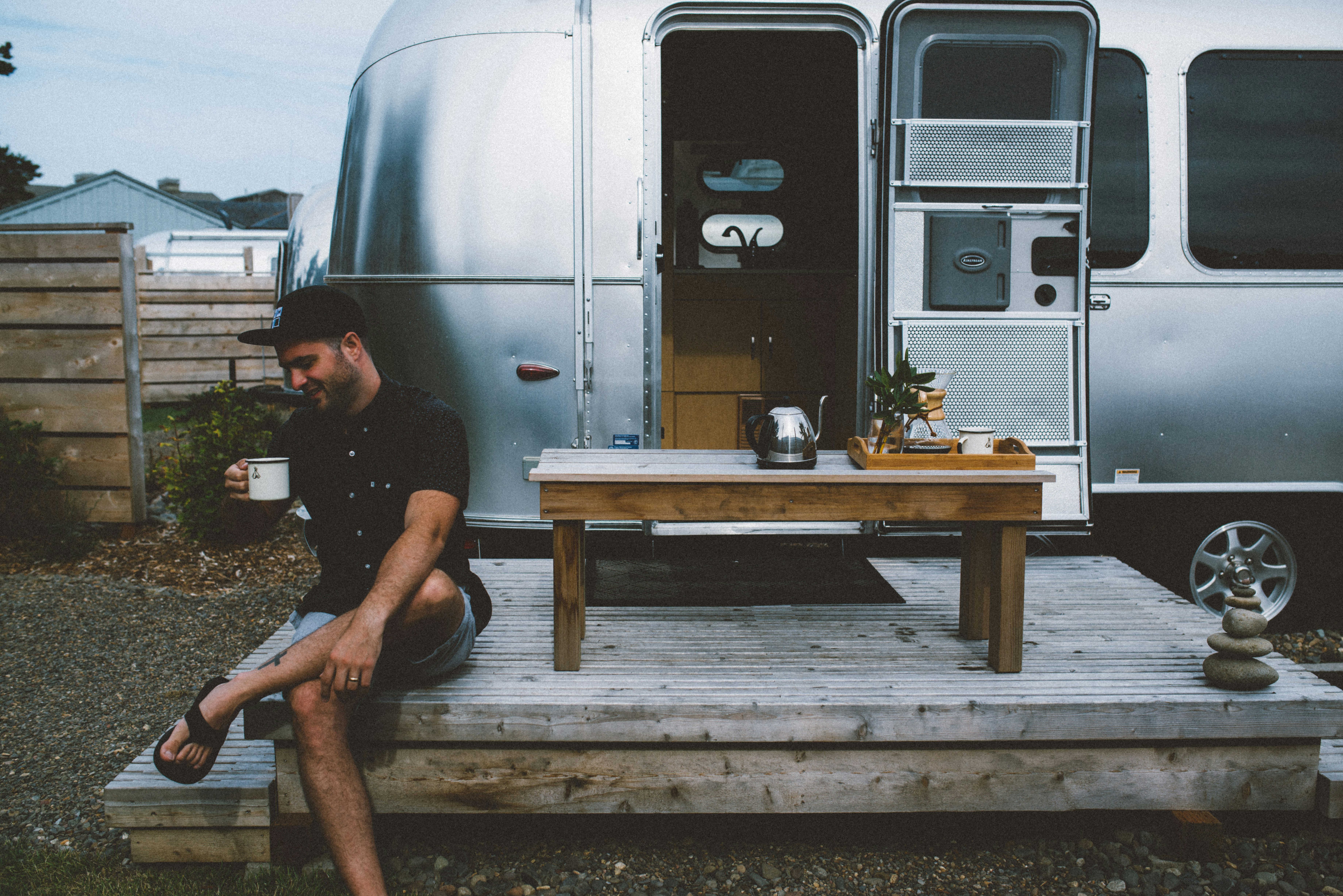 a man sitting on a wooden platform next to a camper