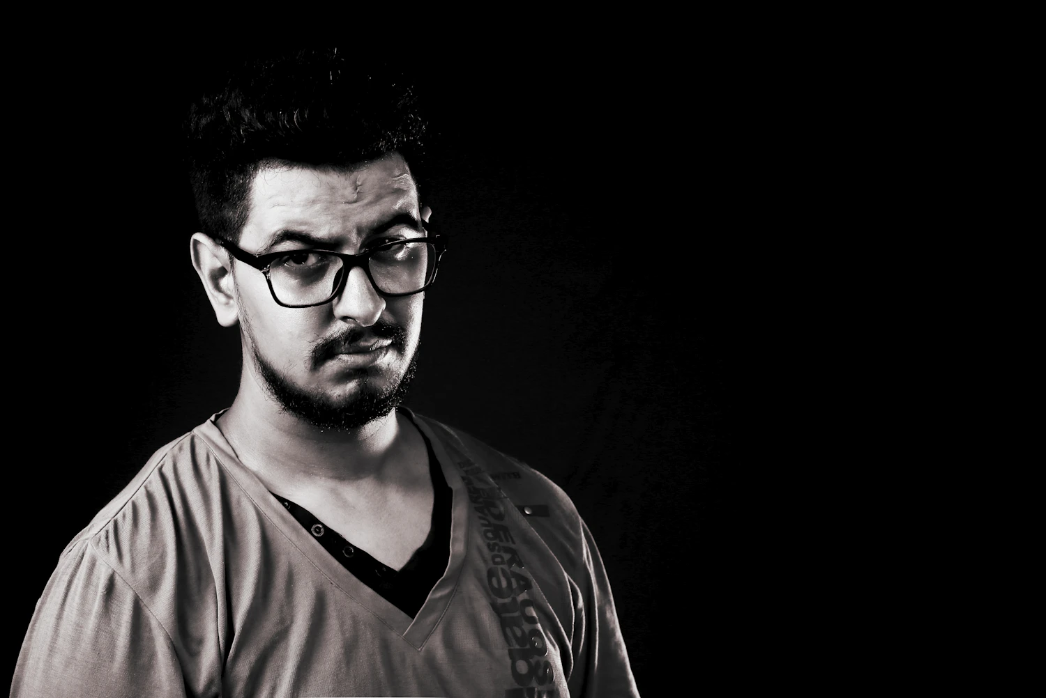 A bassist in his forties with glasses and a beard against a dark background