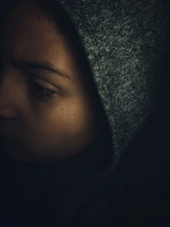 Close-up of the obsidian hoodie’s tonal 3D embroidery on matte black fabric under soft, moody lighting.