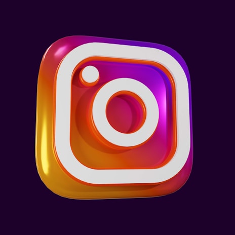 A three-dimensional representation of a multicolored Instagram logo featuring a gradient from pink to orange with a white outline on a dark purple background.