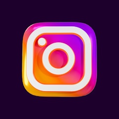 A colorful and glossy 3D representation of a familiar social media logo with a square shape featuring rounded edges and a stylized camera icon in the center. The logo has gradients of pink, purple, and orange with a shiny, reflective surface.