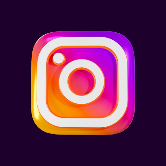 A colorful and glossy 3D representation of a familiar social media logo with a square shape featuring rounded edges and a stylized camera icon in the center. The logo has gradients of pink, purple, and orange with a shiny, reflective surface.