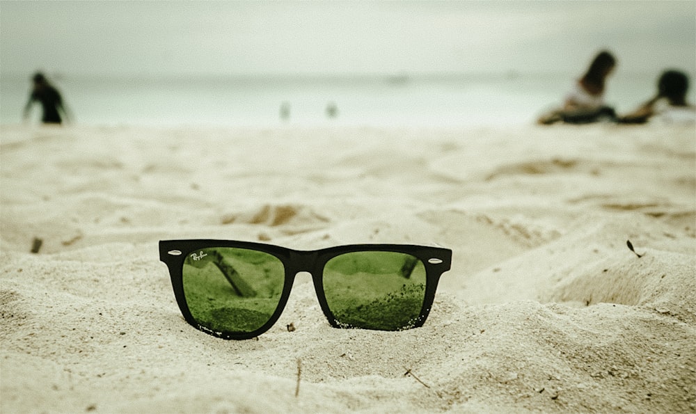 a pair of sunglasses sitting on top of a sandy beach