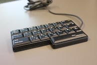 A compact tenkeyless keyboard with stylish keycaps and a matte black finish, angled for easy typing.