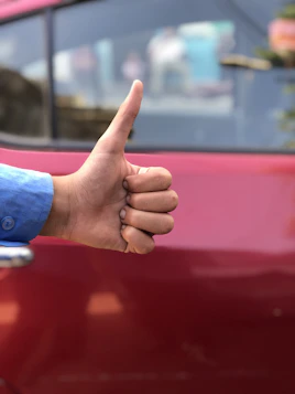 Happy customer shaking hands with a mechanic next to a red car inside the auto center.
