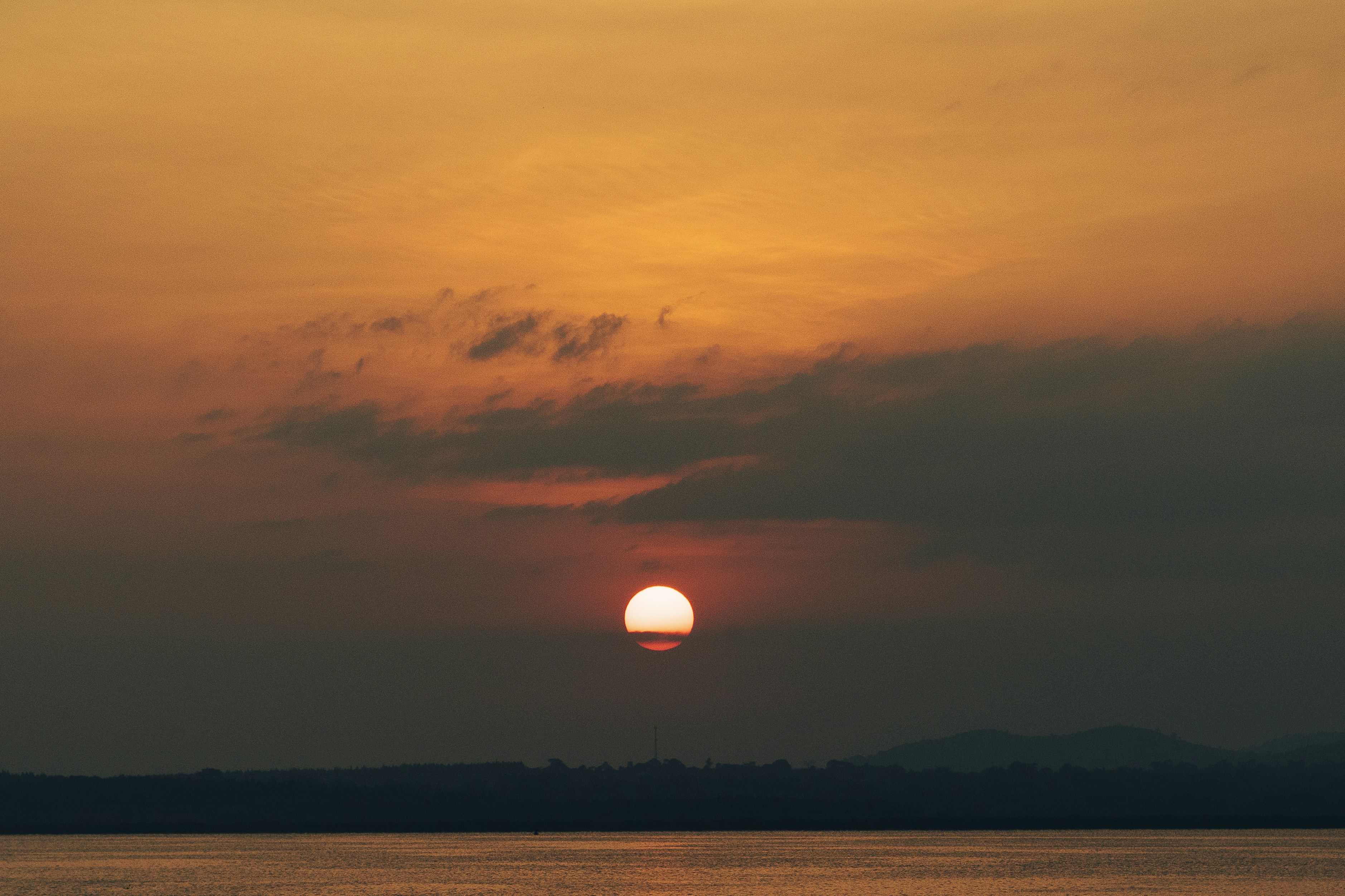 ein großes Gewässer mit einem Sonnenuntergang im Hintergrund